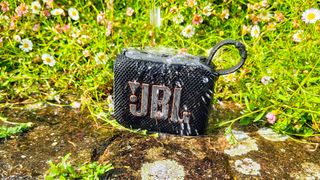 JBL Go 4 splashed with water in a garden