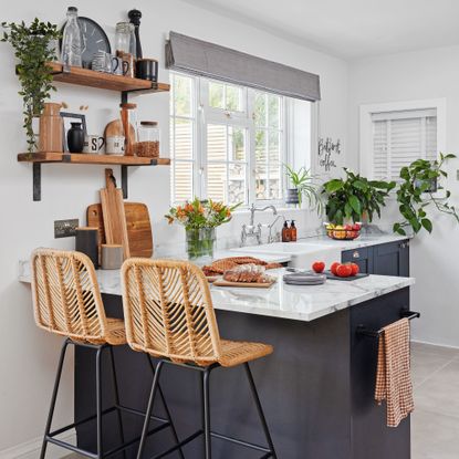 white kitchen with L-shape counter space, open shelving and two rattan stools