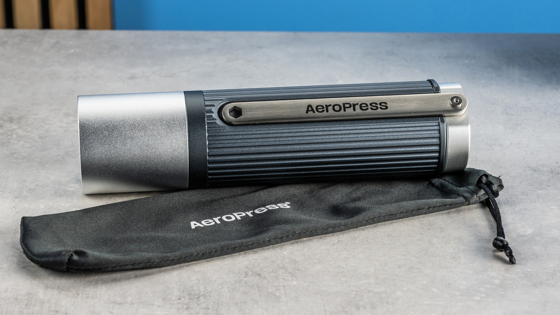 the aeropress manual coffee grinder in gray and silver against the tom's guide blue background