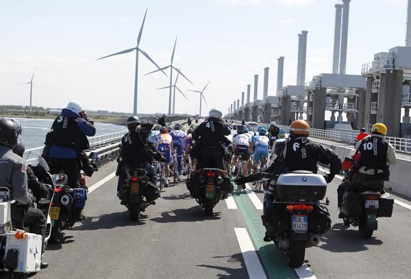 A squadron of motorcycles follow the peloton.