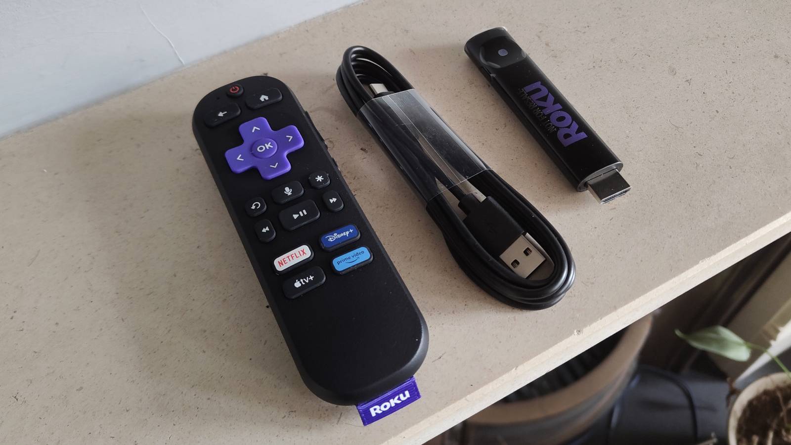 The Roku Streaming Stick next to its remote and adaptor.