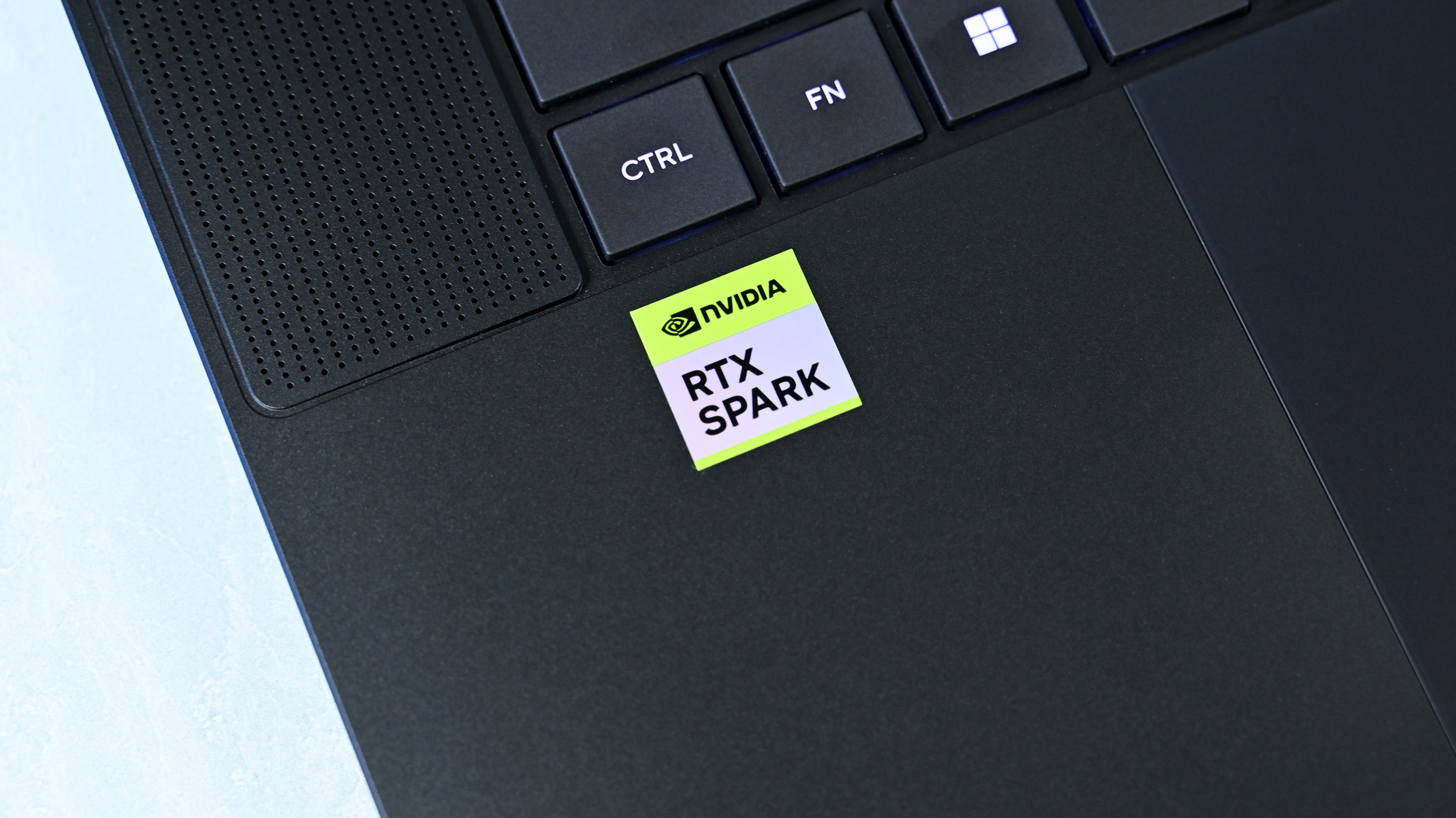 Close-up shot of the green and white NVIDIA RTX SPARK sticker on the matte black chassis next to the keyboard and trackpad