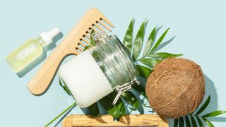 A jar of coconut oil with a hair comb and coconut shell