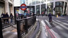 A cyclist passing by a London Underground station