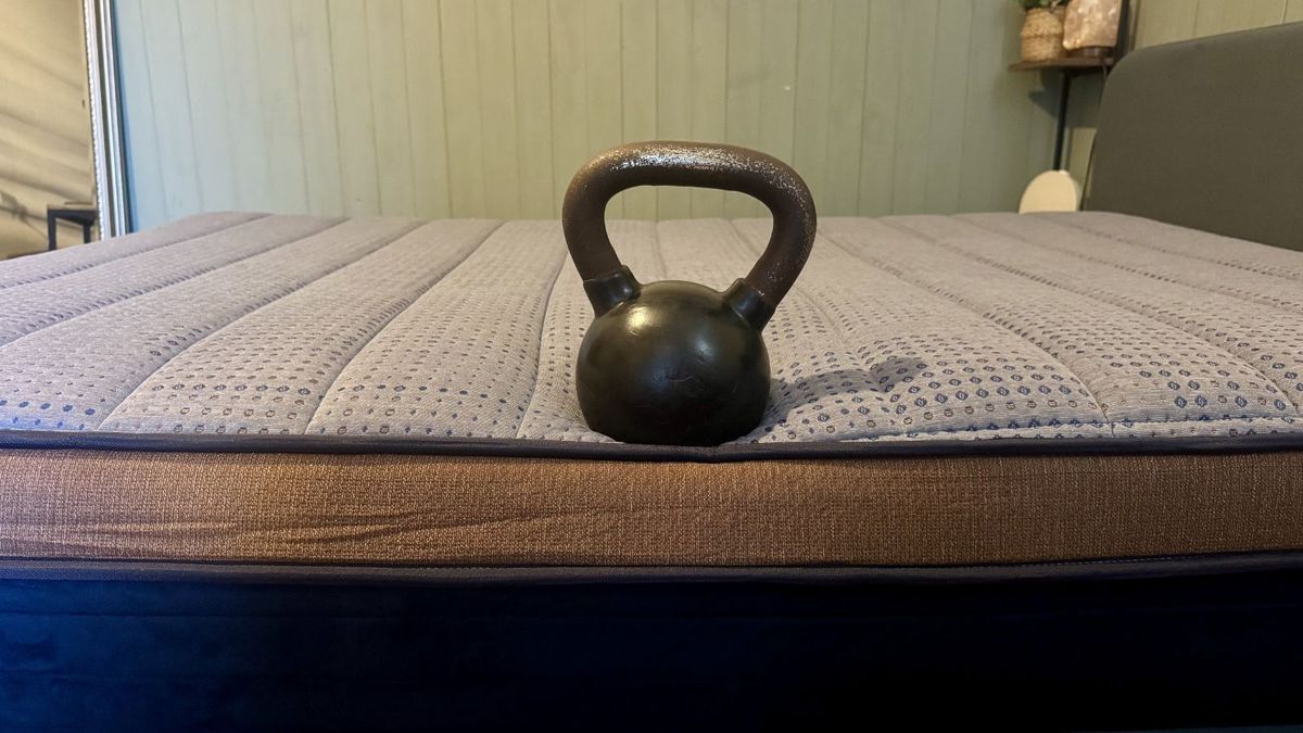 A black and metal kettle bell perched at side of navy and bronze Brooklyn Bedding Copperflex Memory Foam mattress