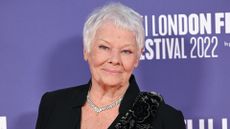 Image of Judi Dench smiling with a short grey pixie cut and wearing a black blazer