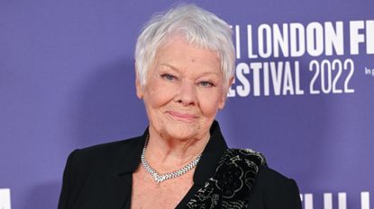 Image of Judi Dench smiling with a short grey pixie cut and wearing a black blazer