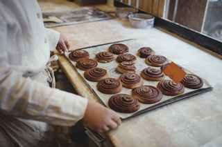 Baker with cinnamon buns on tray
