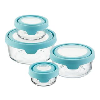 Four different sized glass containers have blue lids on them