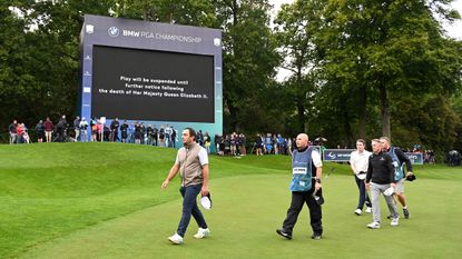 Golfers pictured on the green at Wentworth in front of the announcement that the Queen had died