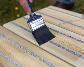 decking boards being painted with paintbrush