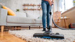 Woman vacuuming a rug in her living room