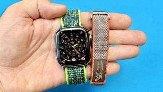 Close-up of the Apple Watch Series 11 next to the Fitbit Air; both are on colorful straps
