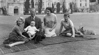 Queen Elizabeth II and Prince Philip, Duke of Edinburgh with their children, Prince Andrew (centre), Princess Anne (left) and Charles, Prince of Wales sitting on a picnic rug outside Balmoral Castle