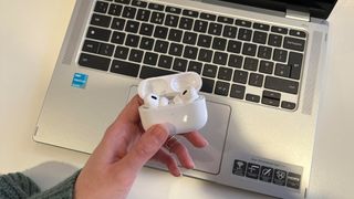 AirPods being held above a Chromebook