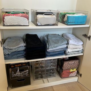 folded clothes on shelves of wardrobe separated by plastic