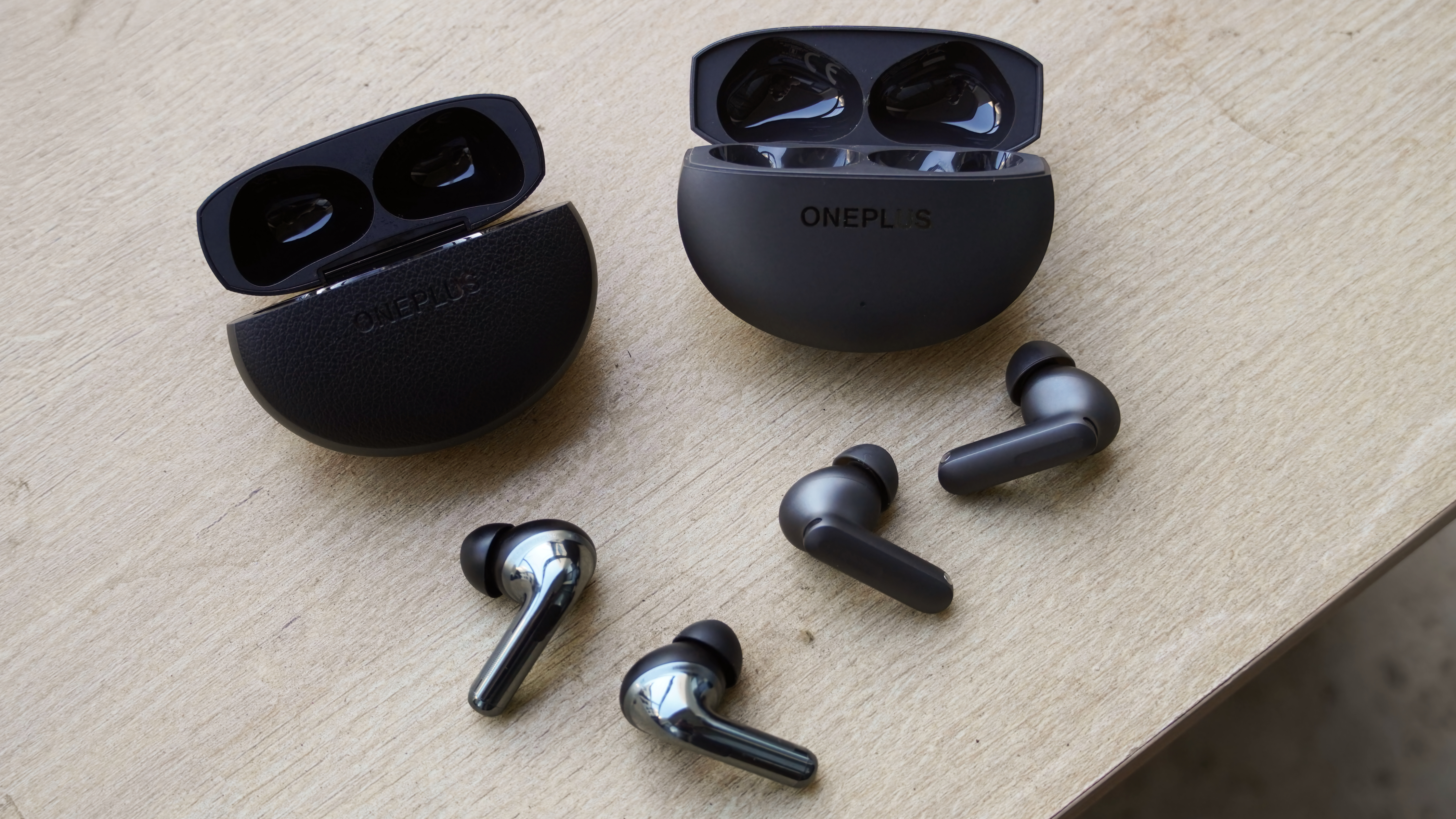 The OnePlus Buds 4 compared with the OnePlus Buds Pro 3 on a table.