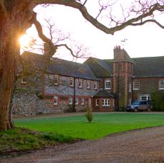 The exterior of Prince William and Princess Kate's country house Anmer Hall at sunset with a tree framing the top of the home