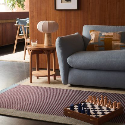 A living room with a powder blue John Lewis sofa and a cushion and a rug with a graphic pattern