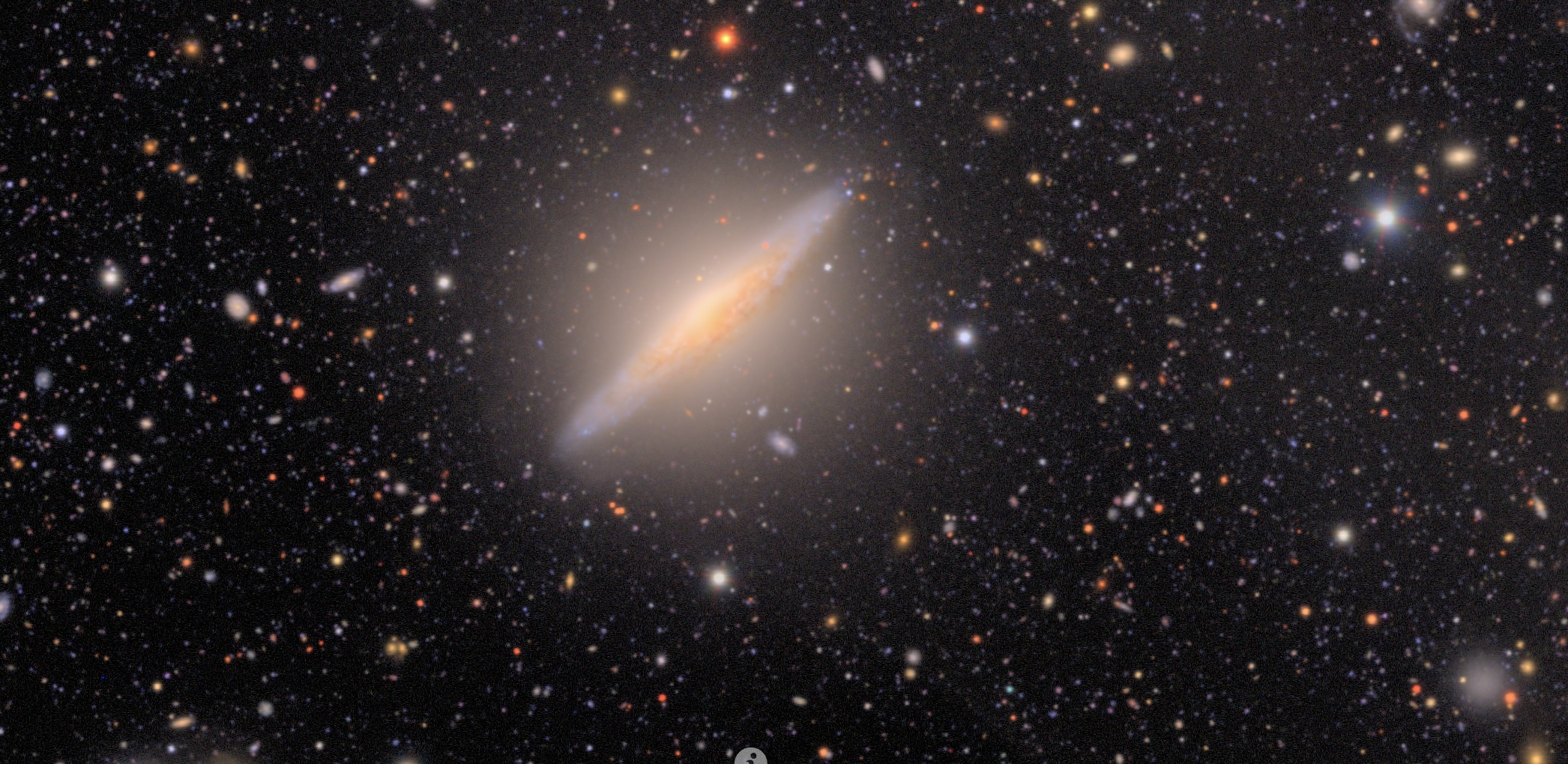 a very flat galaxy against many sparkling stars