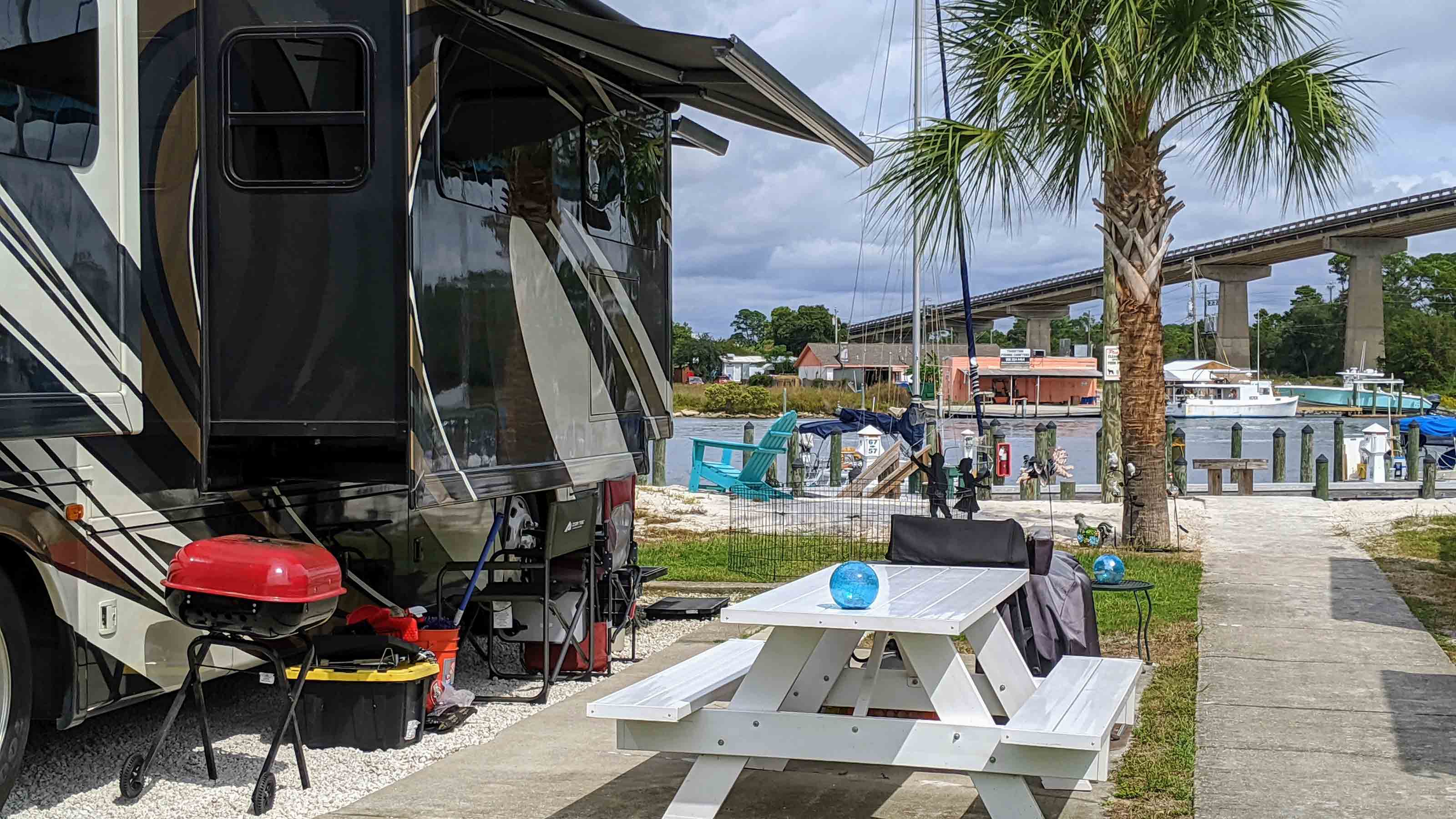 A luxury rv motorhome&amp;#039;s camp site is set up for glamping under a palm tree along the waters in Florida
