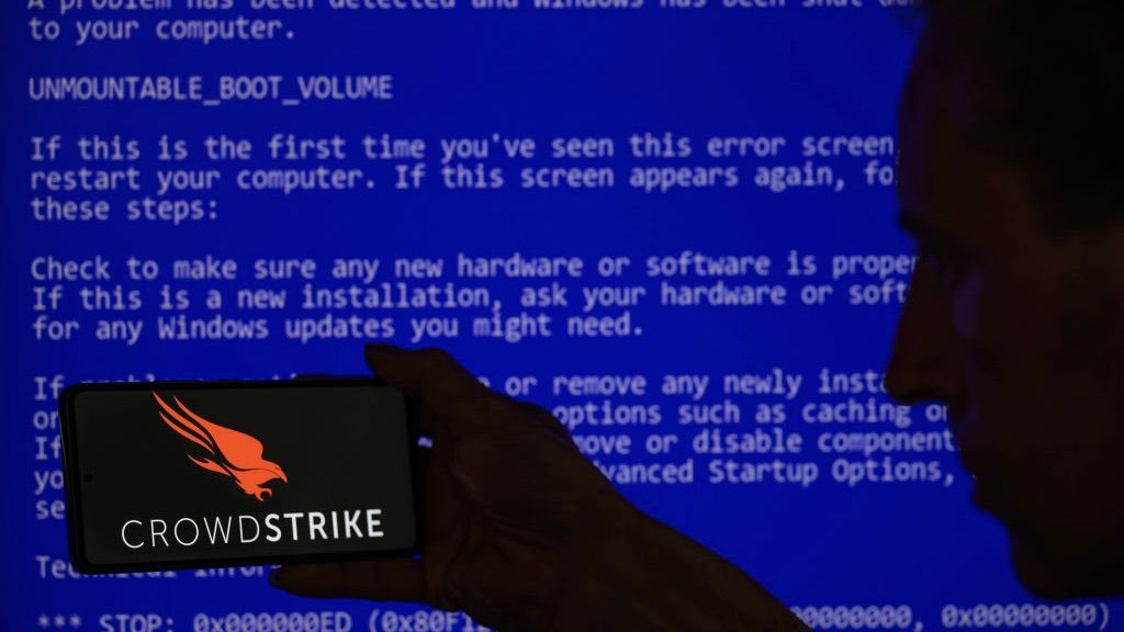 Silhouette of man holding phone with crowdstrike logo infront of blue crash screen