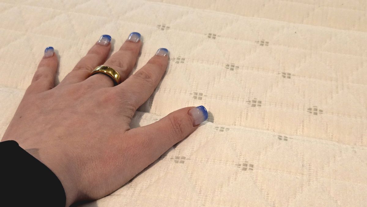 Our tester's hand on the cover of the updated Helix Midnight Mattress
