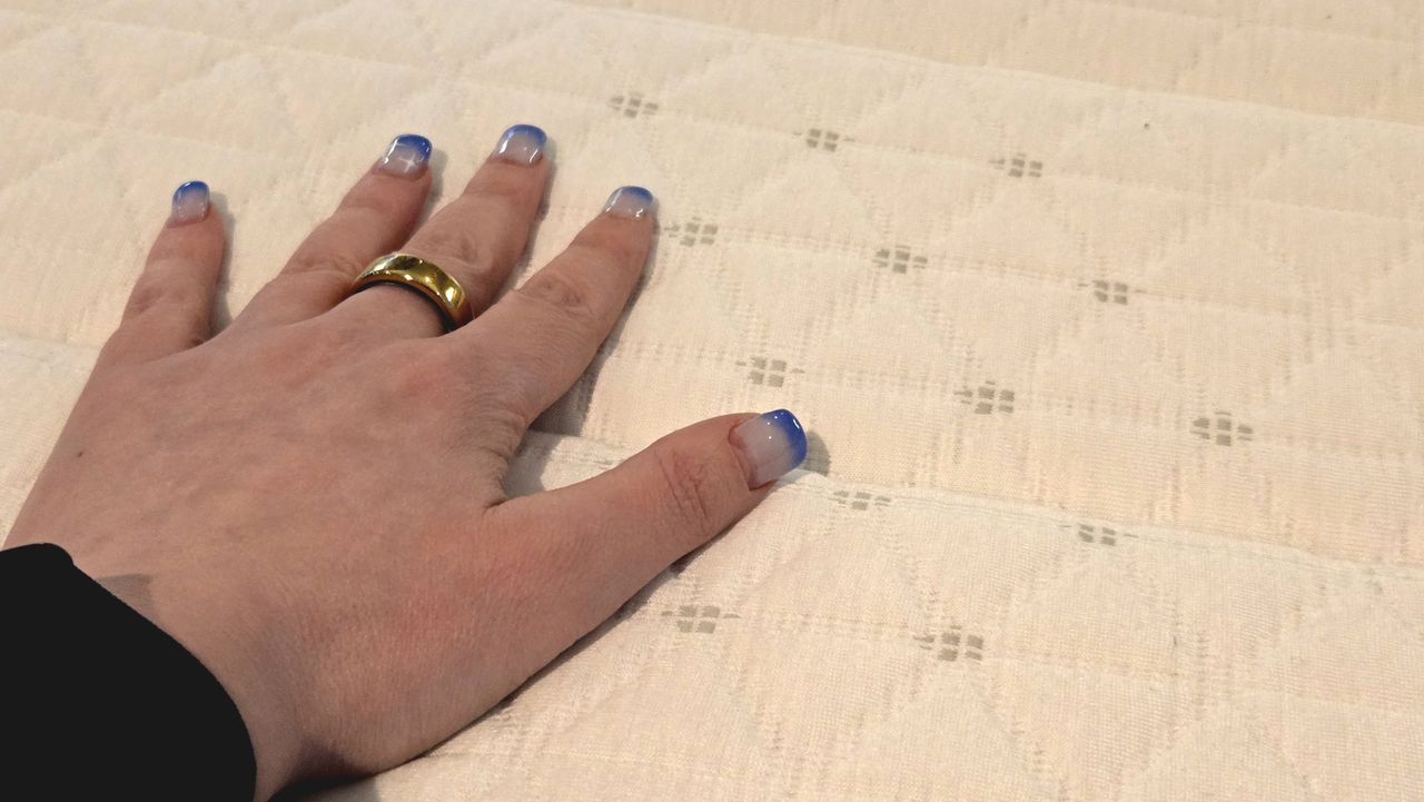 Our tester's hand on the cover of the updated Helix Midnight Mattress