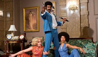 Black Dynamite poses with his gun, his nunchucks, and some ladies