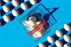 Pattern made of White color Easter Egg and shopping basket on pastel blue color background. Concept of putting most or all of your eggs in one basket, or limiting choices.