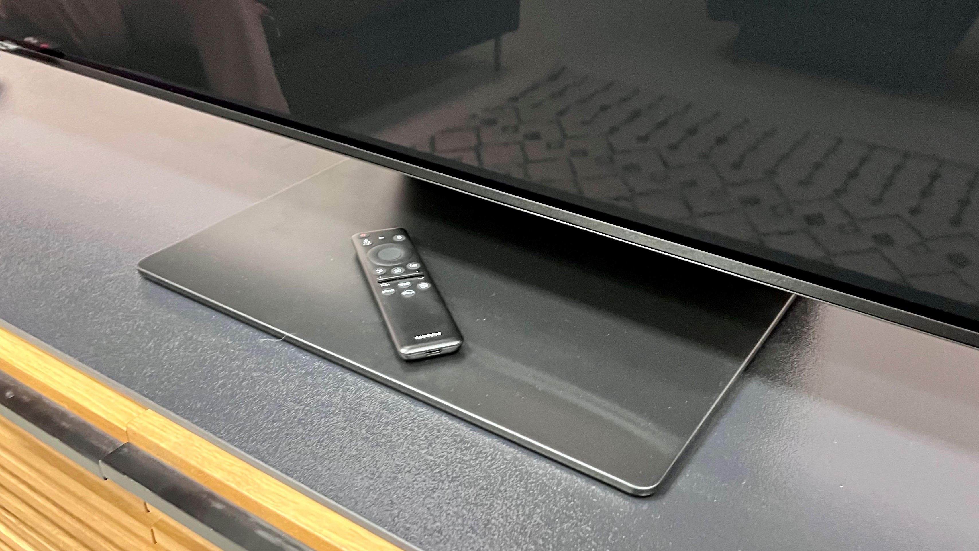 Samsung S95C table stand with remote control on top surface