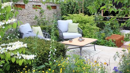 A set of garden chairs surrounded by lush foliage and flowers at RHS Chelsea Flower Show