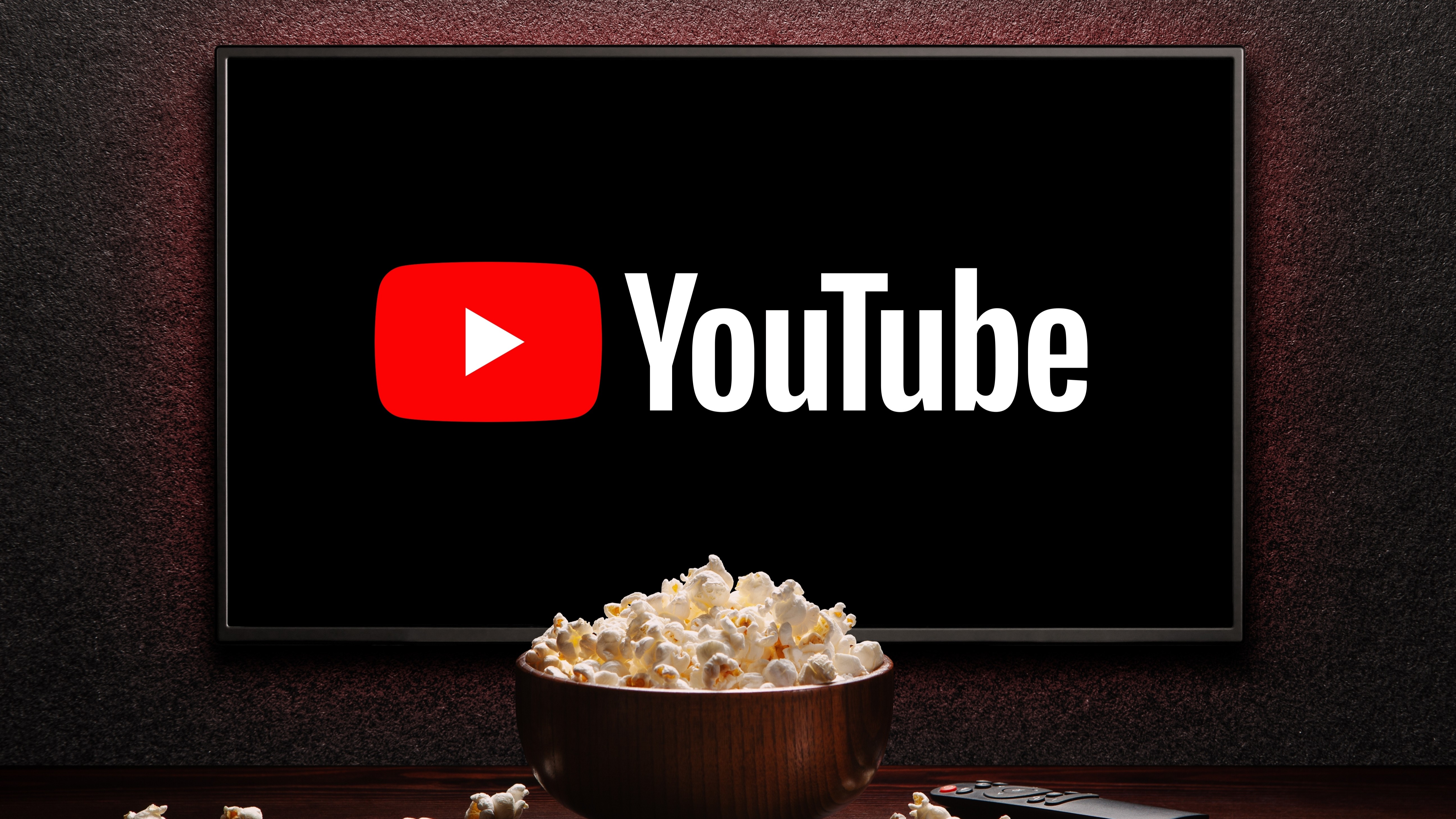 YouTube logo on smart TV with a popcorn bowl and remote control on the table