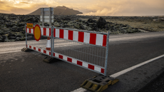 In the center of a road a red and white road blockage blocks the path to the Blue lagoon