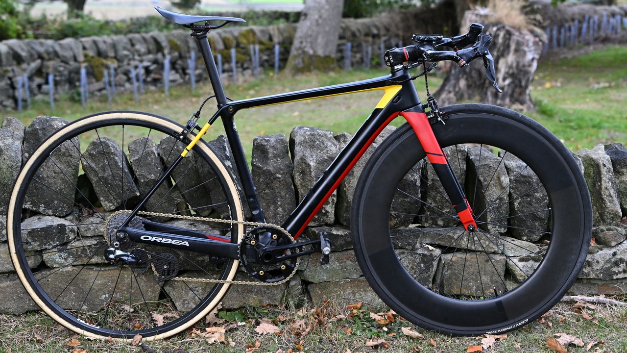 Andy Nicholl&#039;s black and red Orbea Hill Climb bike lent up against a small stone wall