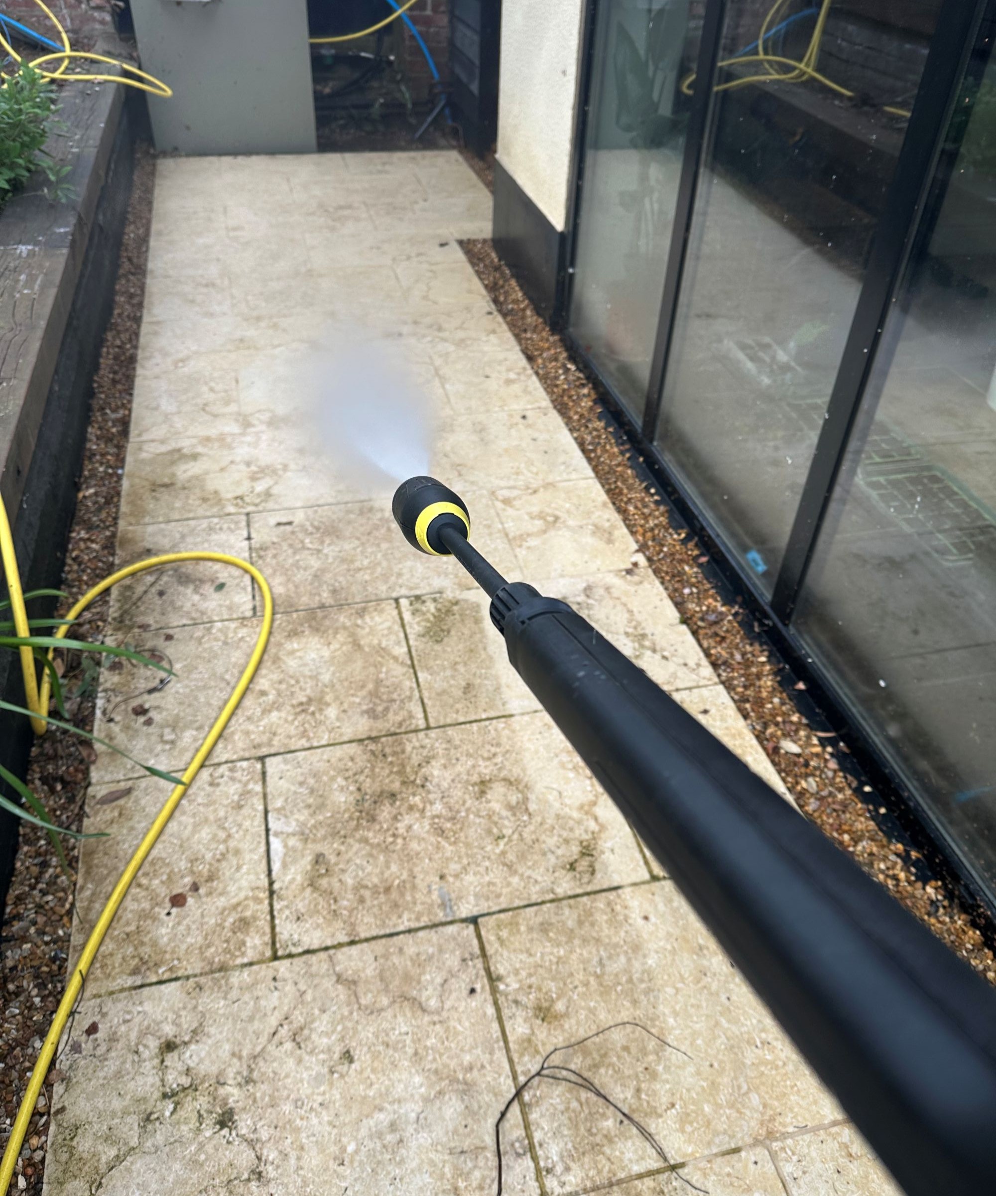 A yellow Karcher K5 Comfort Premium pressure washer on a cream limestone patio