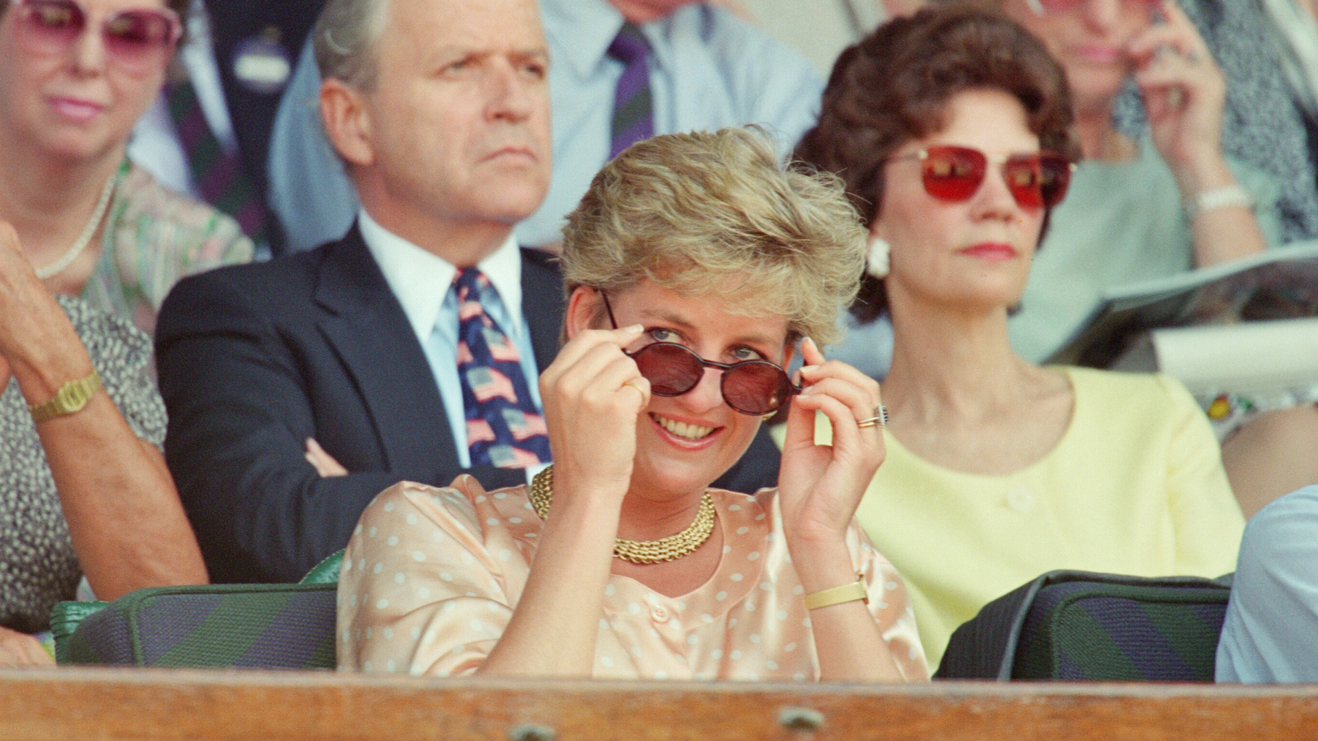 Princess Diana pulling down her sunglasses in a peach top at Wimbledon