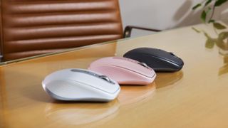 Three Logitech MX Anywhere 3S wireless computer mice sitting diagnolly from each other in a row. The left is grey, the middle is quartz pink, the third on the far right is black.