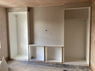 A bare bedroom with an ikea pax in the process of being built against one wall