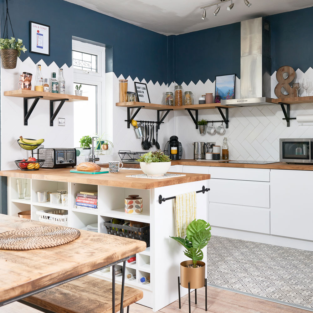 kitchen with multicolour wall and tiles floor and white counter with wooden countertop and wooden shelves