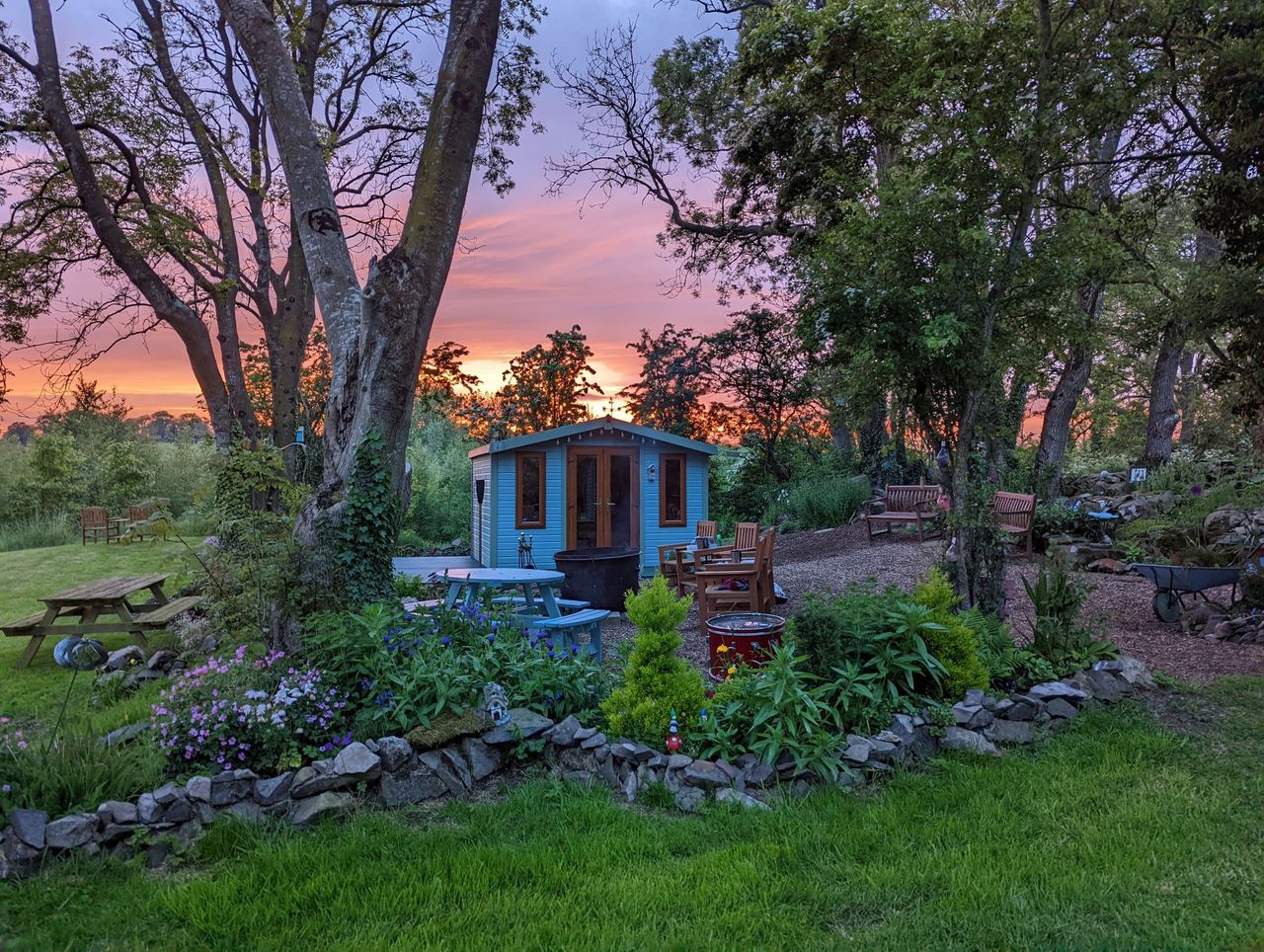 One of the entries for last year's Shed of the Year showing a sunset background for a well lit shed surrounded by a large open field and blue painted wooden shed/wendy house