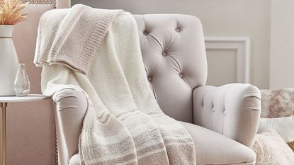 An example of Barefoot Dreams blanket deals, a Barefoot Dreams CozyChic Marled Stripe Blanket on an armchair