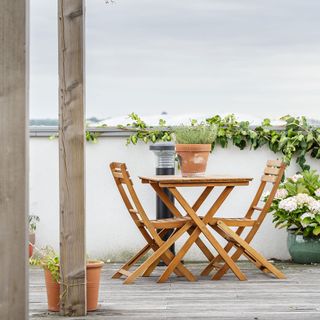 balcony garden with creepers and wooden table and chairs