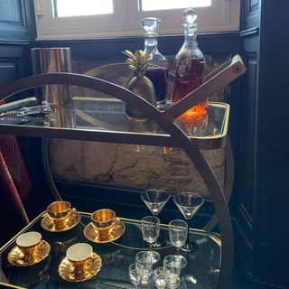 Glass decanter and glasses on top of gold bar cart