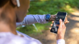 Woman checking running stats on her phone and sports watch