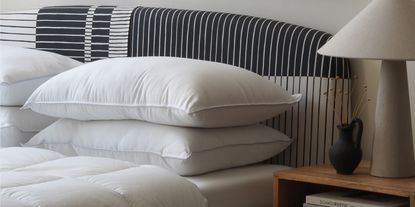 a striped bed head with undressed pillows, and a lamp on a side table