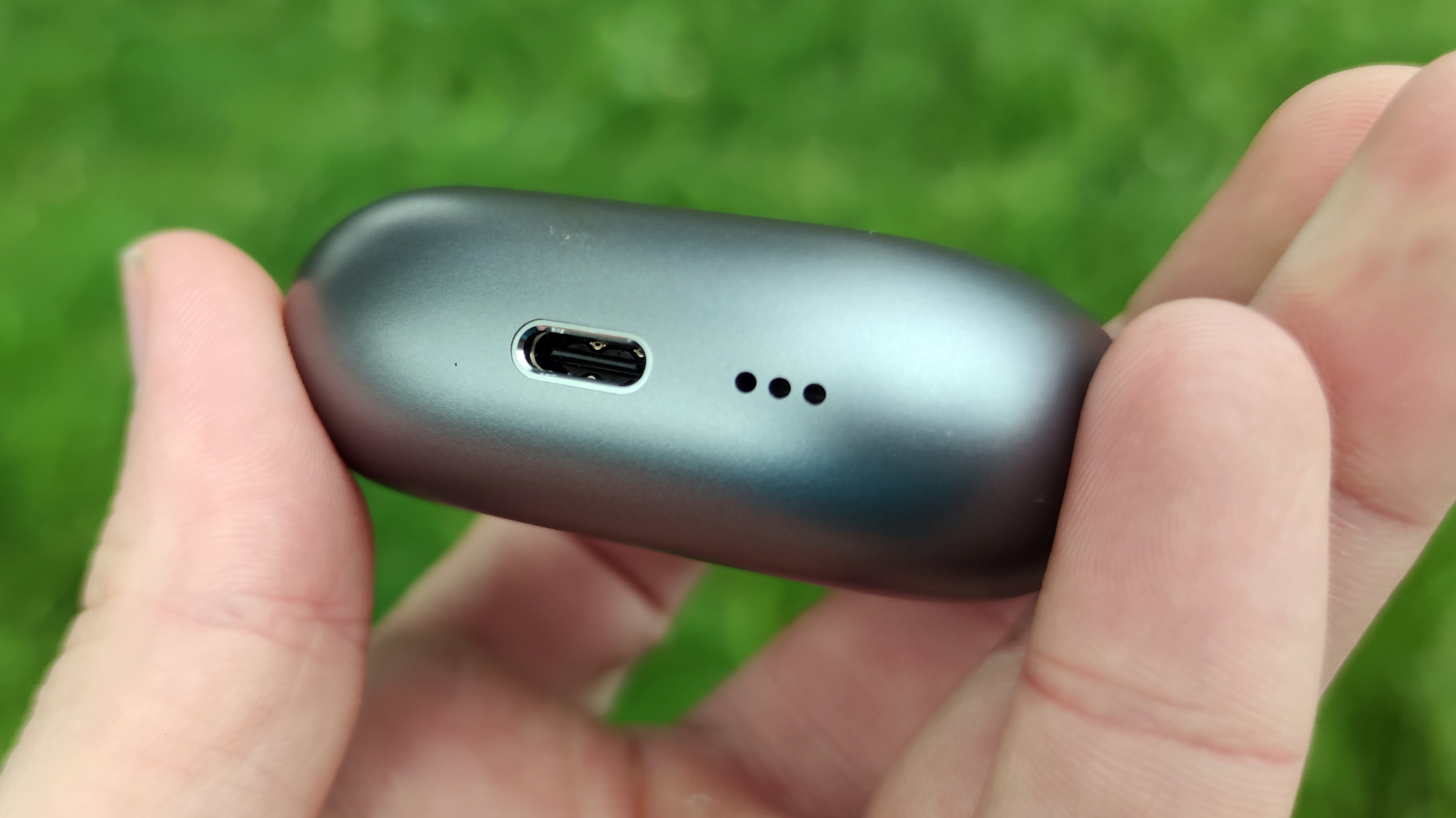 The Huawei FreeBuds Pro 3 being held in a hand above a grassy field.