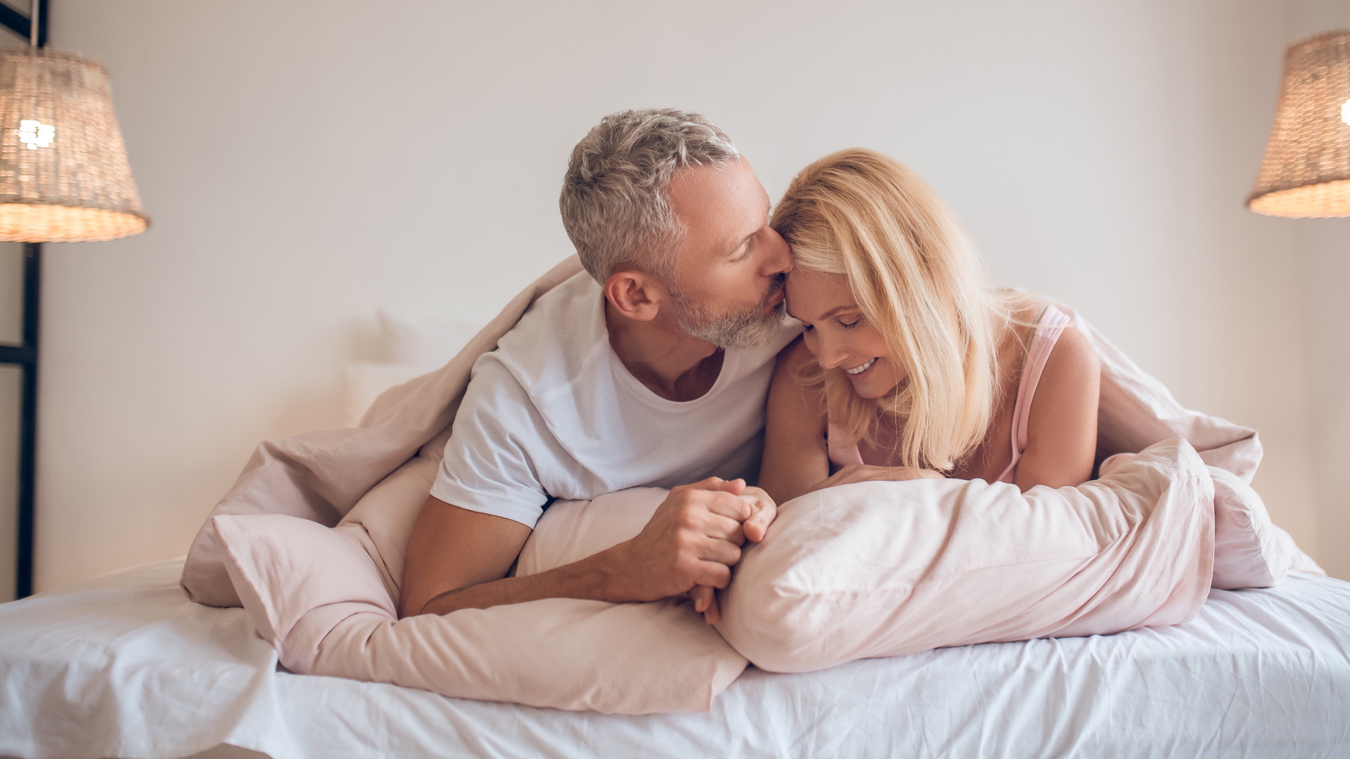 A couple in their 50s cuddling in bed