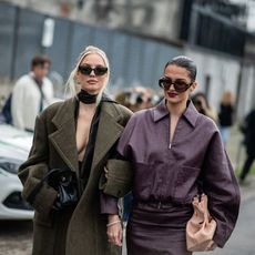 two women in green and purple coats wearing dark sunglasses