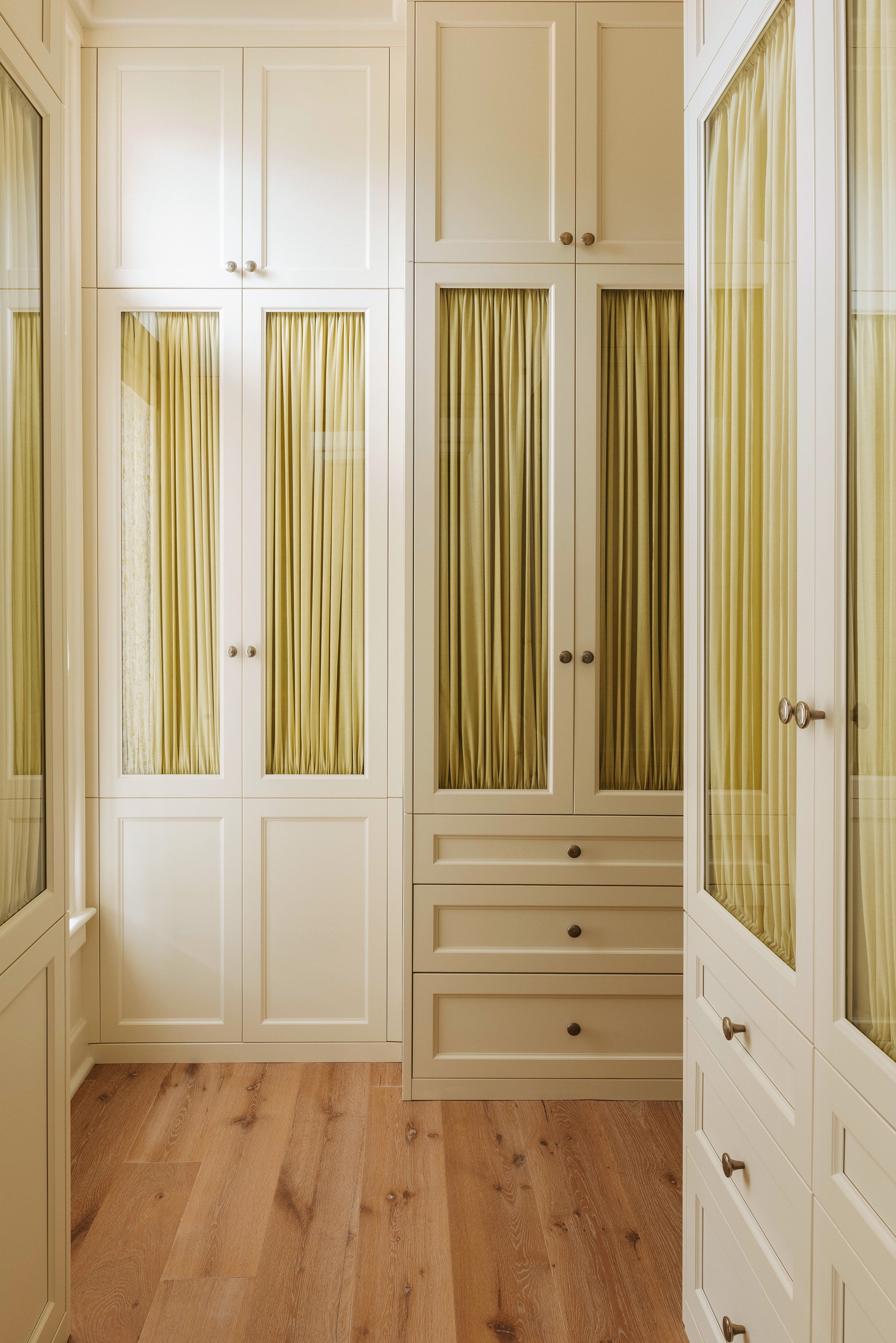 a light yellow closet with yellow curtains inside the glass doors